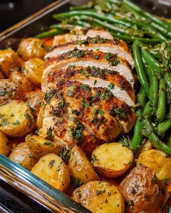 Nahaufnahme von Kräuter-Hähnchenstücken mit Beilagen aus Kartoffeln und grünen Bohnen