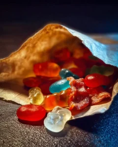 Kindheitserinnerung: Bunte Papiertüte vom Kiosk, prall gefüllt mit verschiedenen Süßigkeiten wie Fruchtgummis und Schaumzucker.