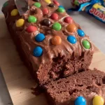 Nahaufnahme der Schokoladenglasur mit bunten M&M’s auf einem Kuchen