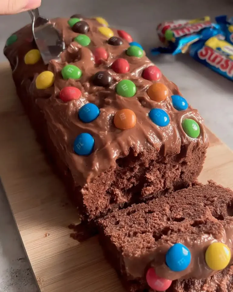 Nahaufnahme der Schokoladenglasur mit bunten M&M’s auf einem Kuchen