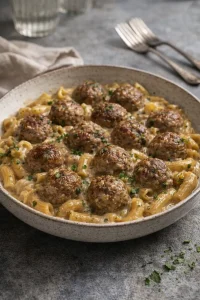 Fleischbällchen mit Eiernudeln auf einem Teller serviert.
