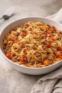 Pasta mit italienischer Wurst und Paprika in einem ansprechenden Teller serviert.